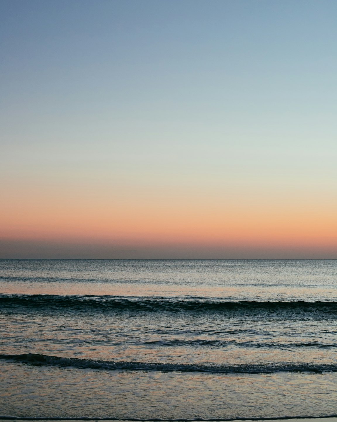 Sunlight reflects on the calm water at the horizon.